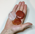 Drei Scheibensteine auf einer Hand liegend: Rosenquarz, roter Jaspis und Karneol