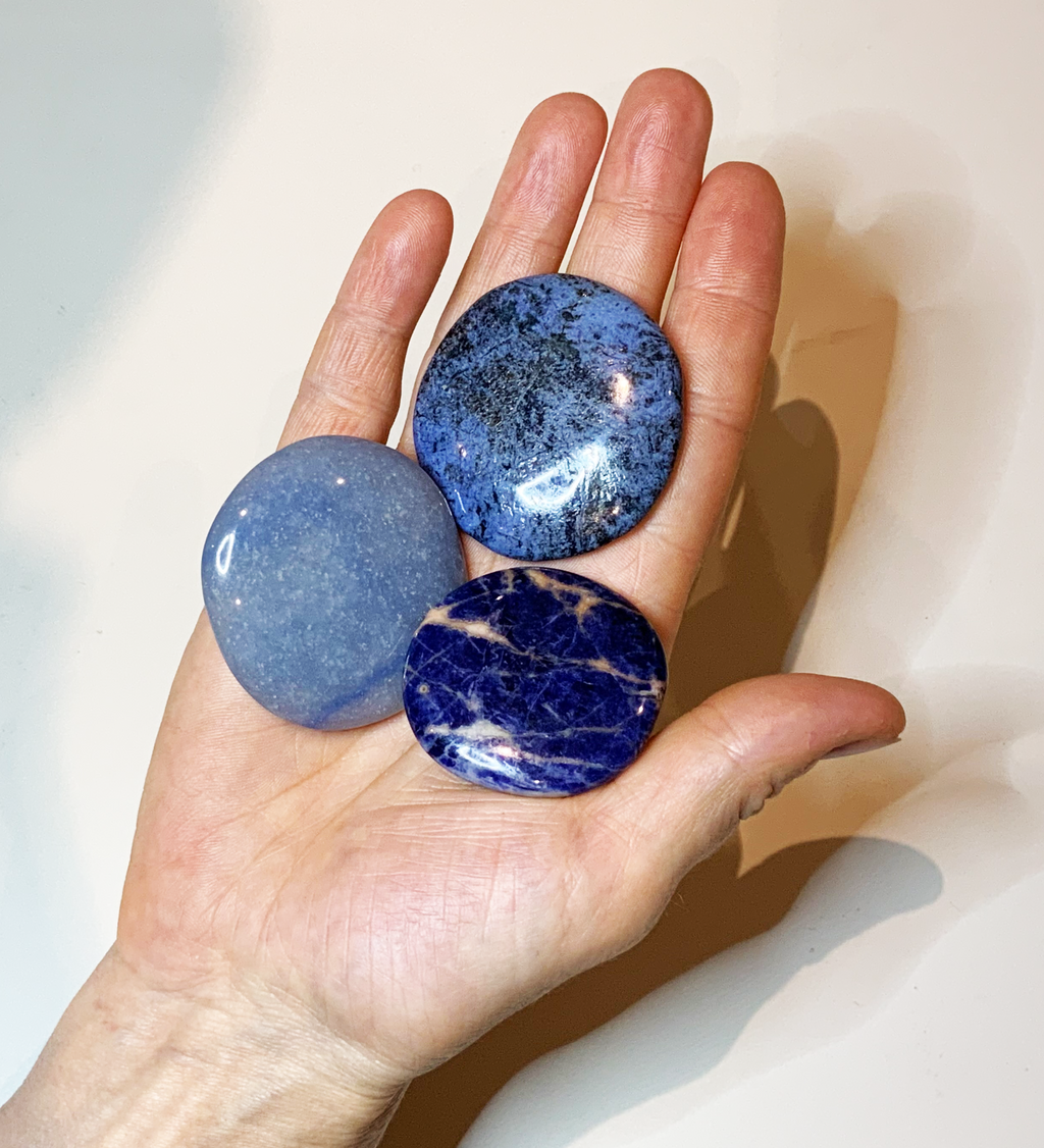 3 blaue Scheibensteine: Sodalith, Dumortierit und Blauquarz in einer Hand liegend