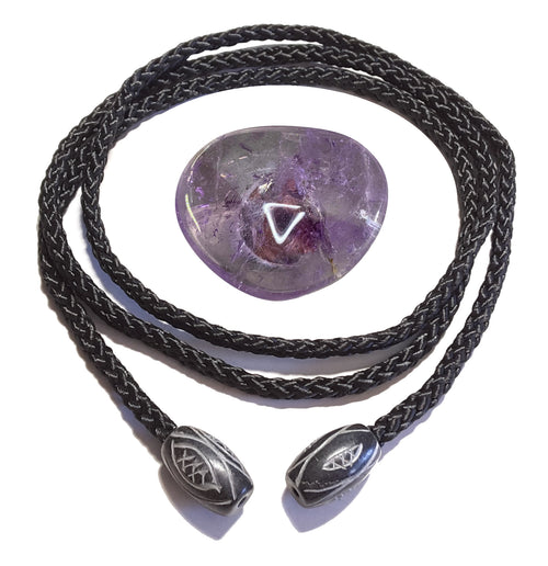 Ein Amethyst-Scheibenstein, eine schwarze geflochtene Kordel und zwei verzierte Endstücke – die Einzelteile einer Cowboykrawatte übersichtlich dargestellt.